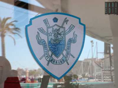 ...bianca e azzurra, richiama l�iconografico �barione�: quello che per alcuni storici sarebbe il primo e pi� antico stemma della citt� di Bari. Si tratta di un cherubino in piedi su una barca nell'atto di scoccare una freccia, naturalmente circondato dal mare...